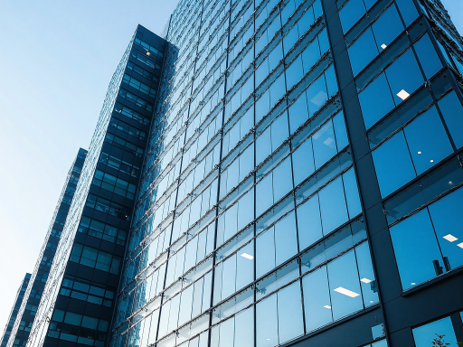 Modern office building exterior with glass facade and corporate signage, bright daylight with clear blue sky